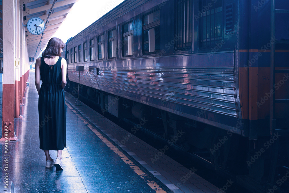 Woman in black dress walking in the pathform at train station
