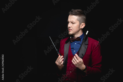 Male magician is experimenting with magic wands using screwdriver tool, black background