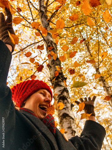 White Caucasian young woman rejoices throws and plays yellow and red autumn leaves.