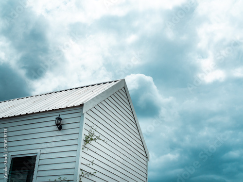 White wooden cabin against the cloud and blue sky background. © tete_escape