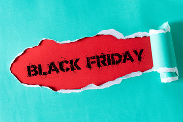 Top view of green pastel torn paper and the text black friday on a red background. Black Friday composition.