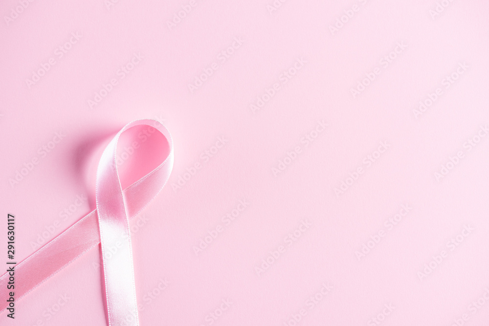 Pink ribbon on pink pastel paper background for supporting breast cancer awareness month campaign.