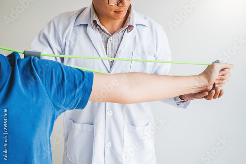 Physiotherapist man giving resistance band exercise treatment About Chest muscles and Shoulder of athlete male patient Physical therapy concept