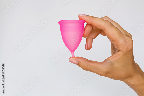 woman holding menstrual cup on white background. Feminine hygiene alternative product instead of tampon during period. Menstruation, critical days, women periods. Zero waste, eco, ecology. photo