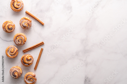 Homemade baked cinnamon rolls with marble slab background and space for text.