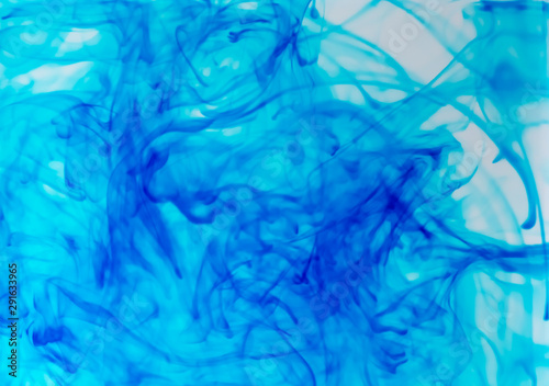 Blurred photo of blue food color drop and dissolve in water for background and texture concept.