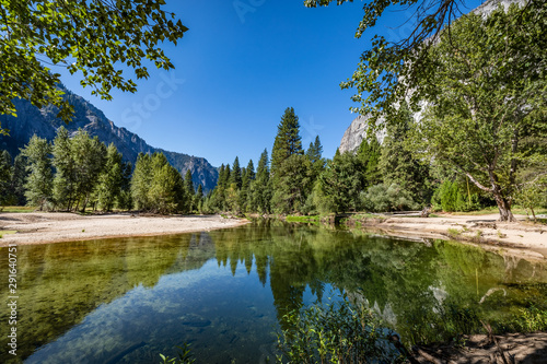 Branches hang from the top in the foreground of Merced River looking towards half dome in Yosemite National Park