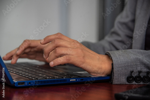 manos de mujer morena trabajadora con telefono celular y laptop azul en oficina