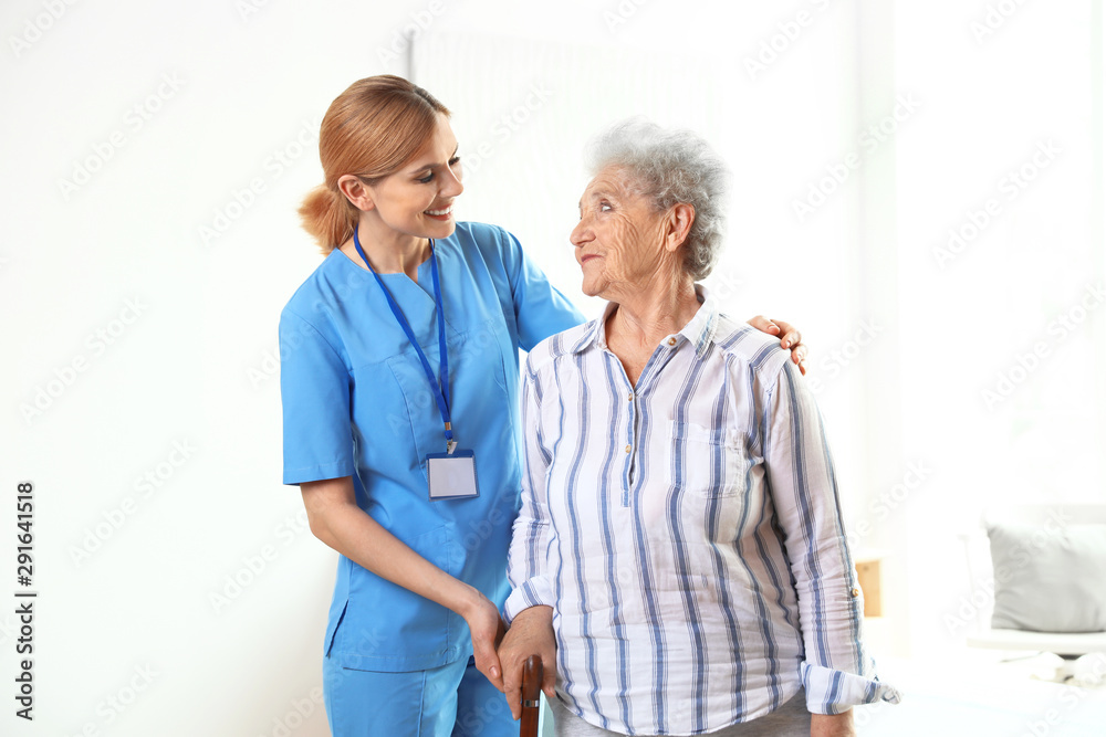 Nurse in uniform assisting elderly woman indoors Nurse in uniform assisting elderly woman indoors