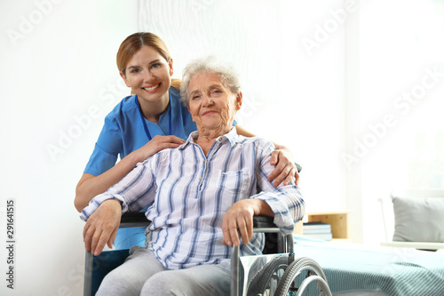 Nurse assisting elderly woman in wheelchair indoors