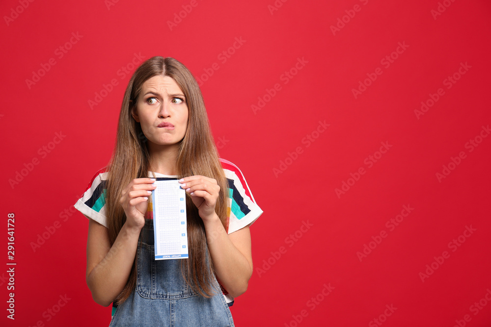 Portrait of emotional young woman with lottery ticket on red background, space for text Portrait of emotional young woman with lottery ticket on red background, space for text