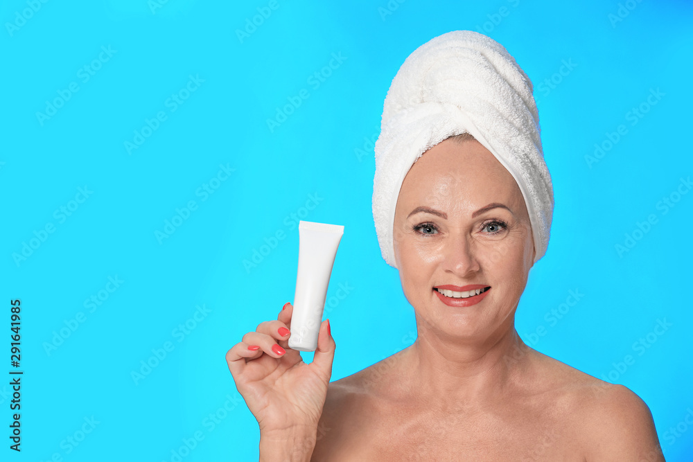 Portrait of beautiful mature woman with perfect skin holding tube of cream  on light blue background Photos | Adobe Stock