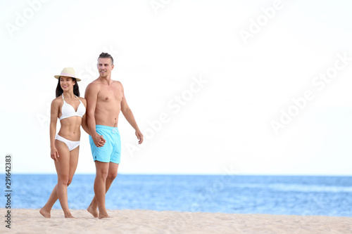 Young woman in bikini spending time with her boyfriend on beach. Lovely couple