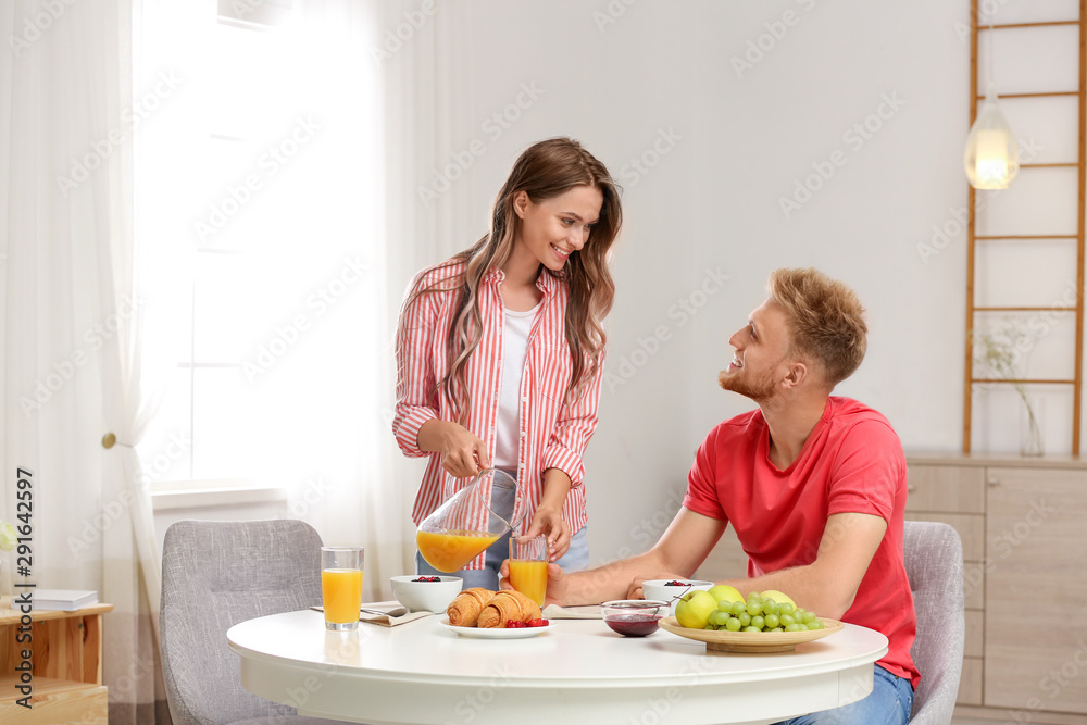 Happy young couple having breakfast at table in room