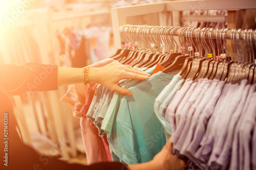 shopping, clothing. Suit shop, Raw of different colors man's suit or jackets hanging on apparel which blurred backgrounds 