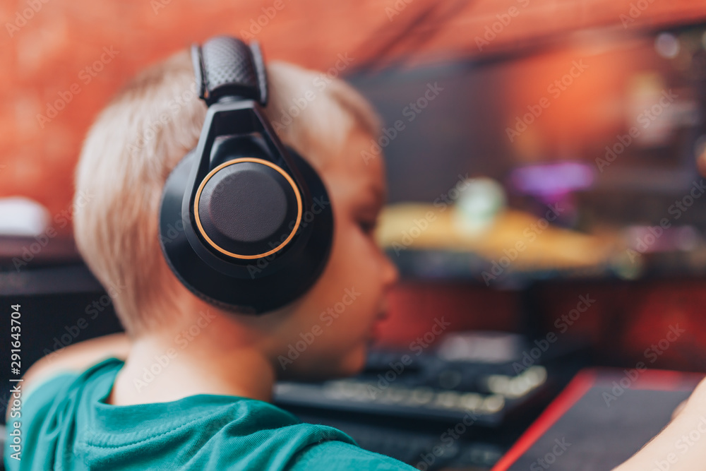 little boy playing games on computer in headphones with microphone, computer game little boy playing games on computer in headphones with microphone, computer game