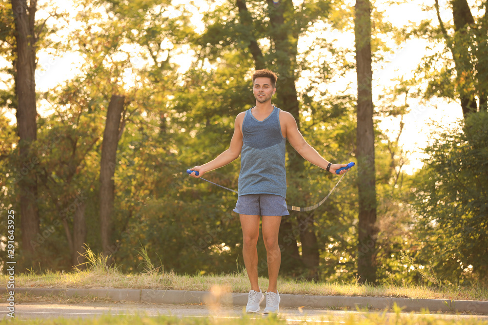 Young man training with jump rope in park