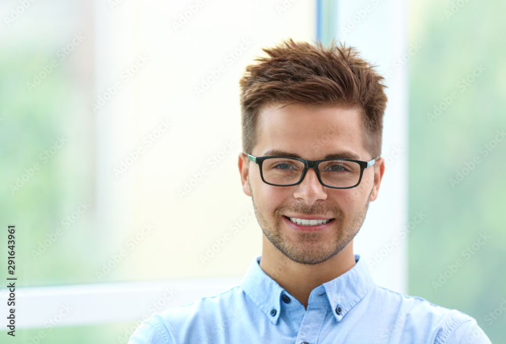 Obraz premium Portrait of handsome young man with glasses near window