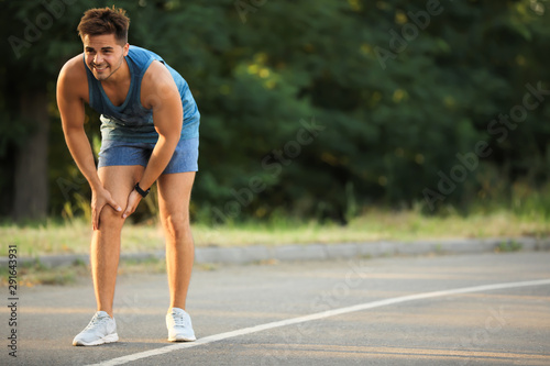 Young man in sportswear having knee problems in park © New Africa