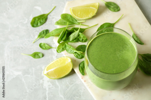 Glass of healthy green smoothie with fresh spinach on light table, above view