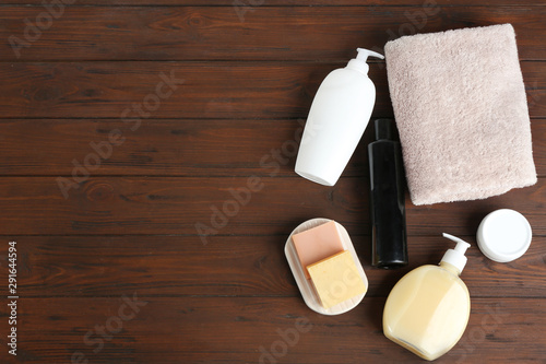 Folded soft towel and toiletries on wooden background, flat lay. Space for text
