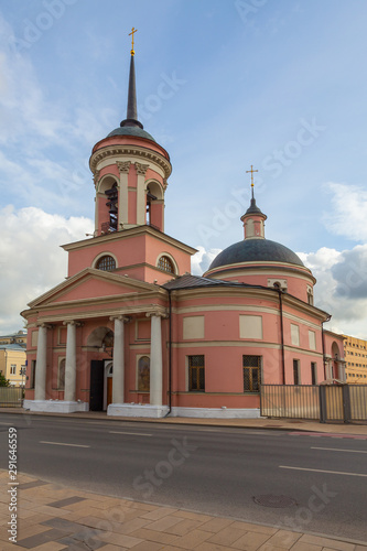 An old pink Orthodox church against the blue sky with light clouds (vertical image)