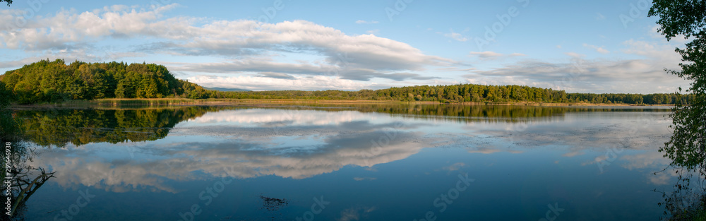 Beautiful panorama of autumn lake against the background of forest and sunny sky