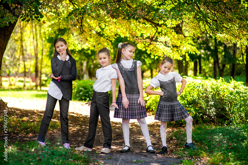 Schoolchildren have fun in the park. Four girls in school uniform are jumping and laughing © Kiryakova Anna