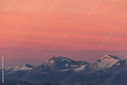 Mountain top covered by snow with a beautiful orange sky on the background © Massimo