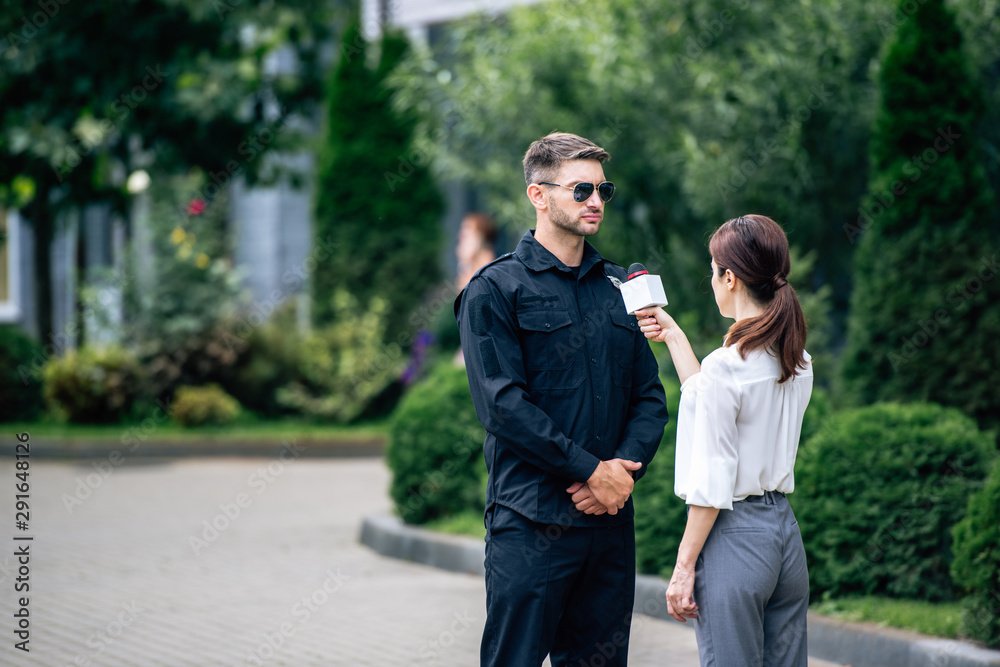 journalist holding microphone and talking with handsome policeman in uniform journalist holding microphone and talking with handsome policeman in uniform