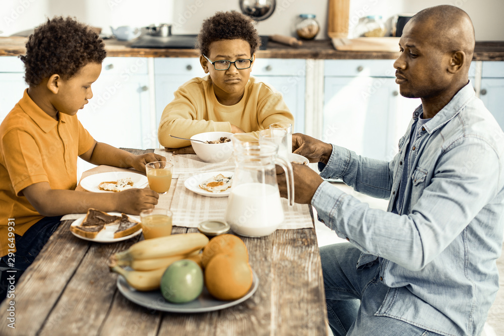 Dad and his son trying to persuade the older one to having breakfast. Dad and his son trying to persuade the older one to having breakfast.