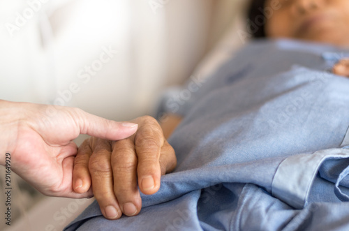 Elderly female hand holding hand of young caregiver at nursing home.Geriatric doctor or geriatrician concept. Doctor physician hand on happy elderly senior patient to comfort in hospital examination