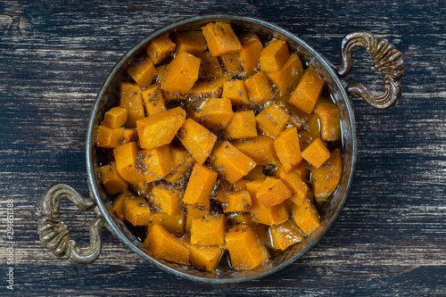 Baked yellow pumpkin with honey, anise, olive oil and spices on a plate on the wooden table. Vegetarian food. Closeup