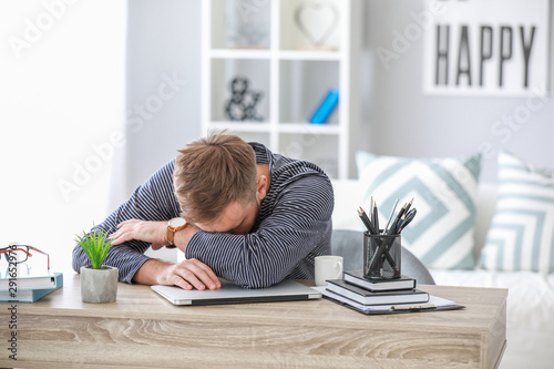 Stressed young man at table...