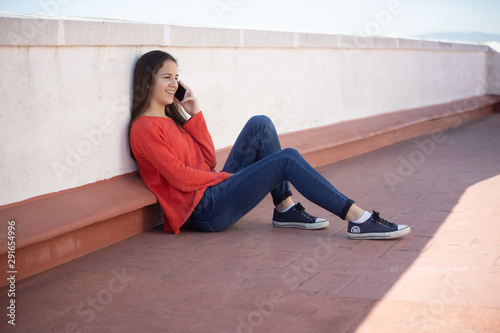 Bild auf Leinwand Chica adolescente feliz hablando por teléfono móvil sentada en la azotea