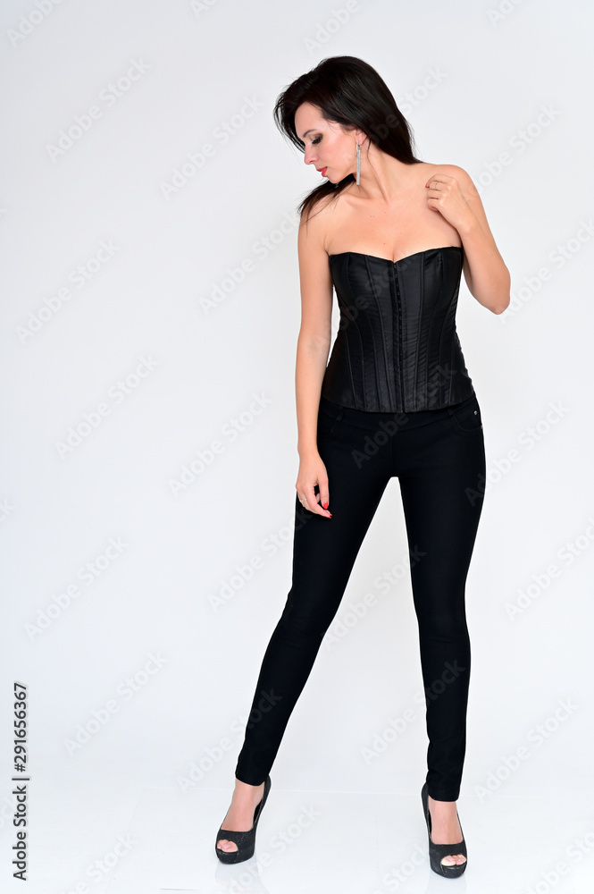Full-length vertical portrait of a sexy brunette woman in black clothes on a white background. It is in different poses. Great makeup and beautiful hair. Full-length vertical portrait of a sexy brunette woman in black clothes on a white background. It is in different poses. Great makeup and beautiful hair.