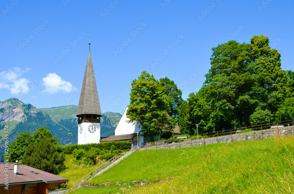 Beautiful Protestant church in Alpine resort Wengen, Switzerland photographed in the summer with green landscape. Mountains in the background. Alpine landscape, Swiss Alps