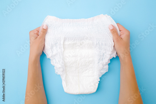 Foto Woman hands holding white adult diaper on pastel blue background