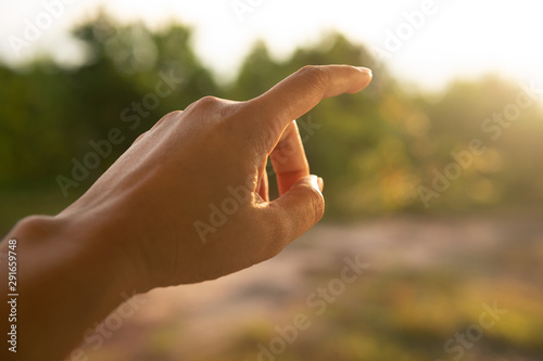 pointing woman hand to the soft nature morning sunlight background © bidala