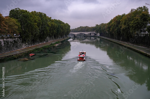 Rome, river tiber view with tourists on traditional boat, italy