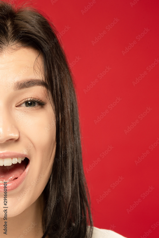 Caucasian young woman's close up portrait on red studio background. Beautiful female model with well-kept skin. Concept of human emotions, facial expression. Looks happy, smiling. Caucasian young woman's close up portrait on red studio background. Beautiful female model with well-kept skin. Concept of human emotions, facial expression. Looks happy, smiling.