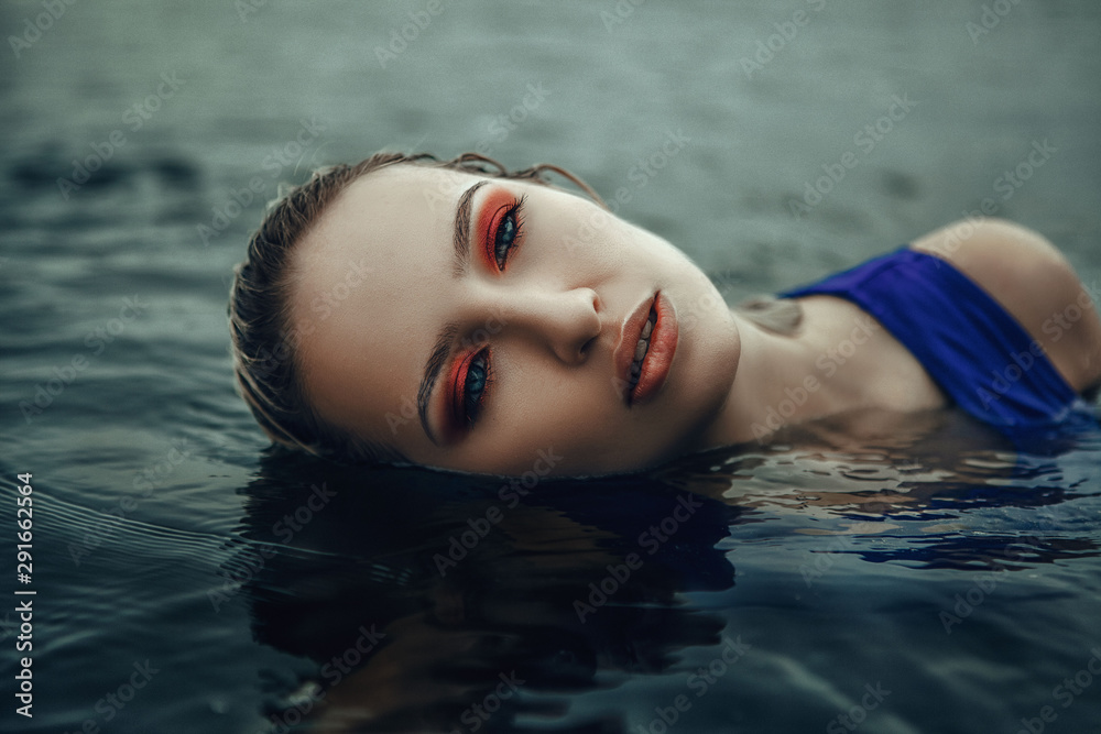 Young lady wearing a dress is posing in a water