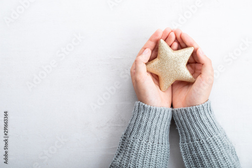 Christmas star decor in women hand. Christmas greeting card. Woman's hands hold christmas or new year decorated gift.