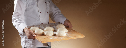 Baker or chef carrying a tray of dough portions