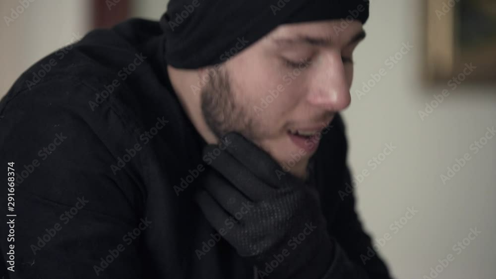 Close-up of young caucasian thief in black clothes thinking on the next crime. The guy stealing things in rich house. Concept of offense against the law Close-up of young caucasian thief in black clothes thinking on the next crime. The guy stealing things in rich house. Concept of offense against the law