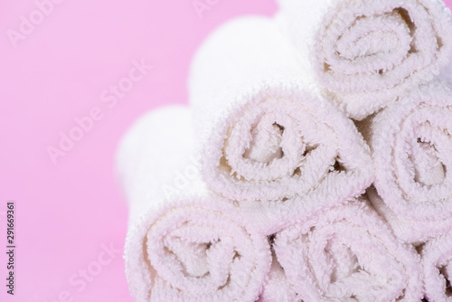 Gently rolled terry towels for spa or massage on a pink background