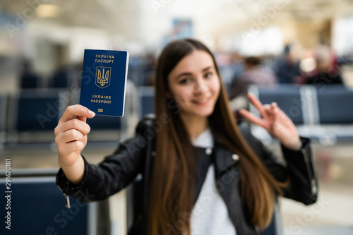 Young happy woman holding Ukraine passport in terminal of airport