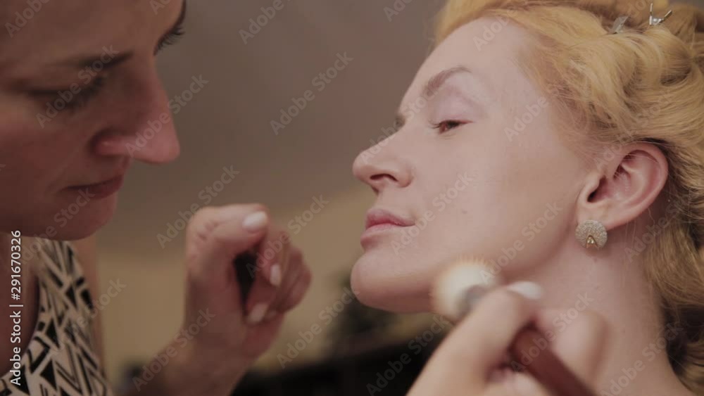 Professional make-up artist applies make-up photo of model to woman.