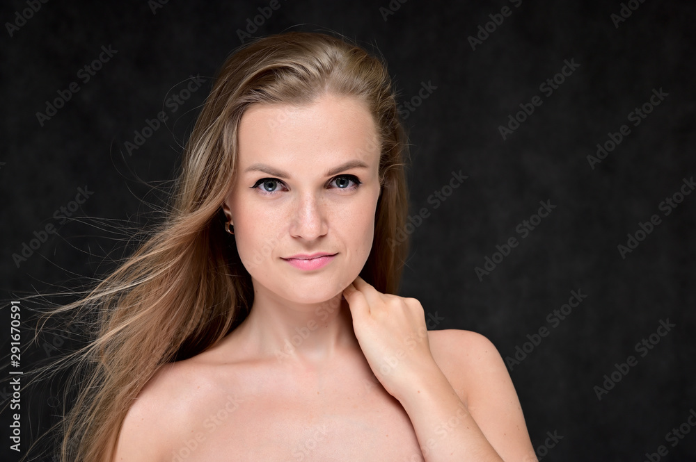 Close-up portrait of a beautiful girl with long hair and excellent skin on a gray background. Close-up portrait of a beautiful girl with long hair and excellent skin on a gray background.