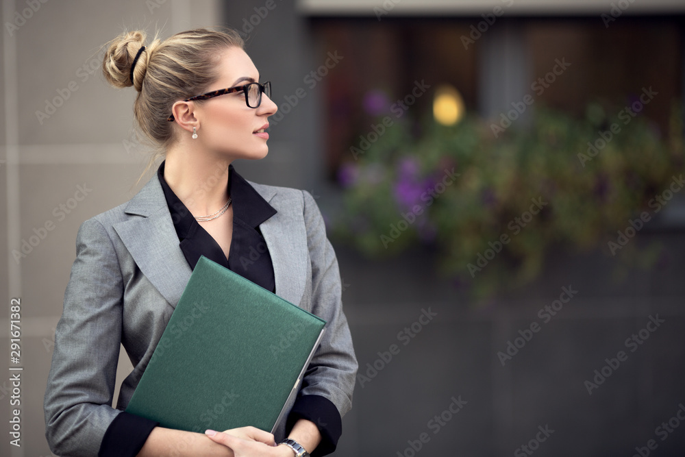 Young successful woman in formal suit. Woman in the city holds a file Young successful woman in formal suit. Woman in the city holds a file